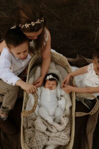 Adelaide siblings looking at their new baby sister in a mosses basket.