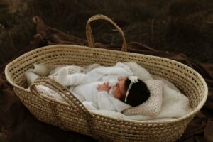 Adelaide siblings looking at their new baby sister in a mosses basket.