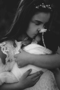 An Adelaide girl holding and kissing her baby sister.