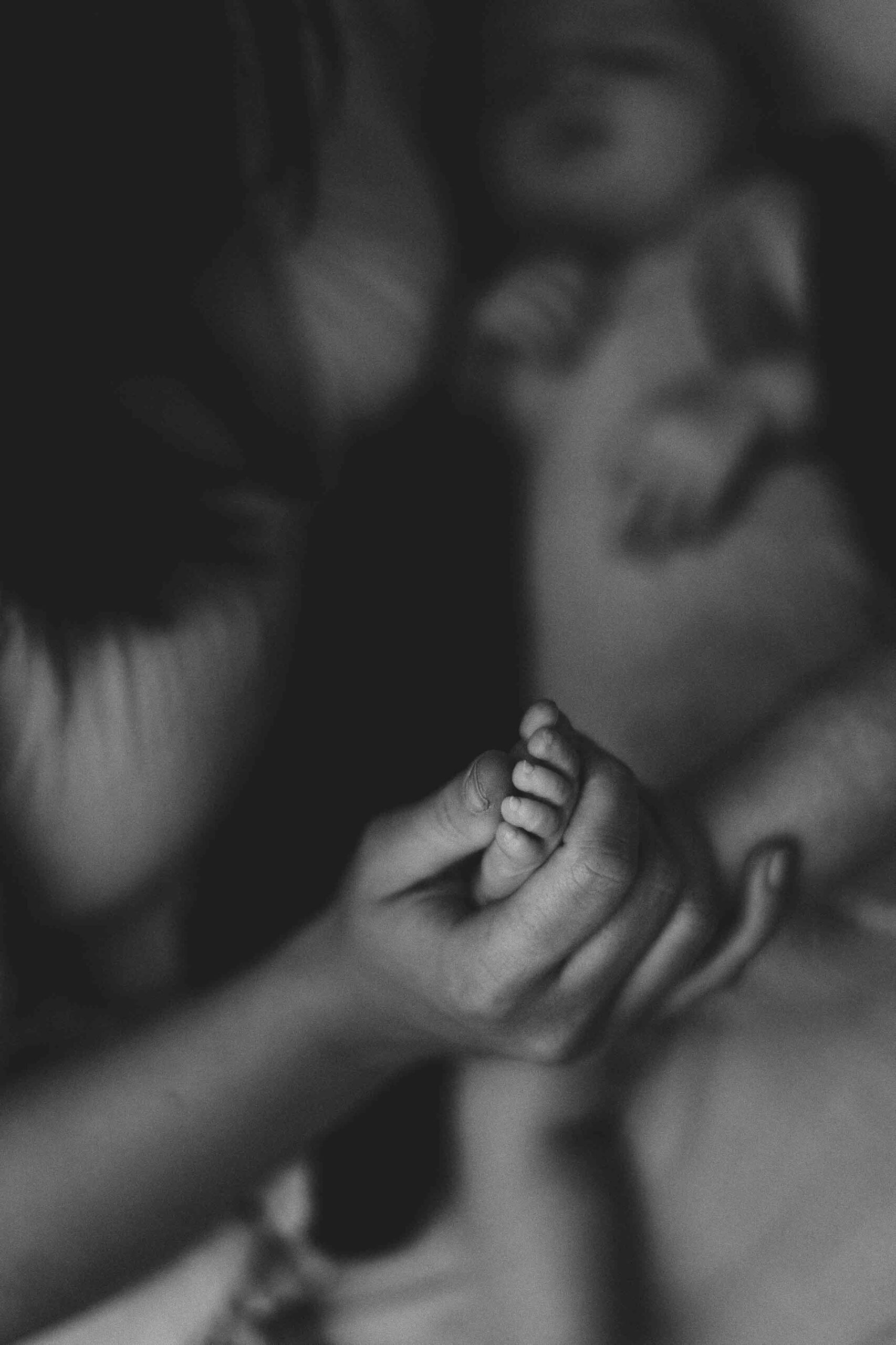 A mum holding the foot of her 12 week old baby girl in an Adelaide newborn studio.