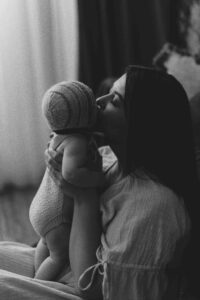 An Adeliade mum holding up her 12 week old baby and giving her a kiss.