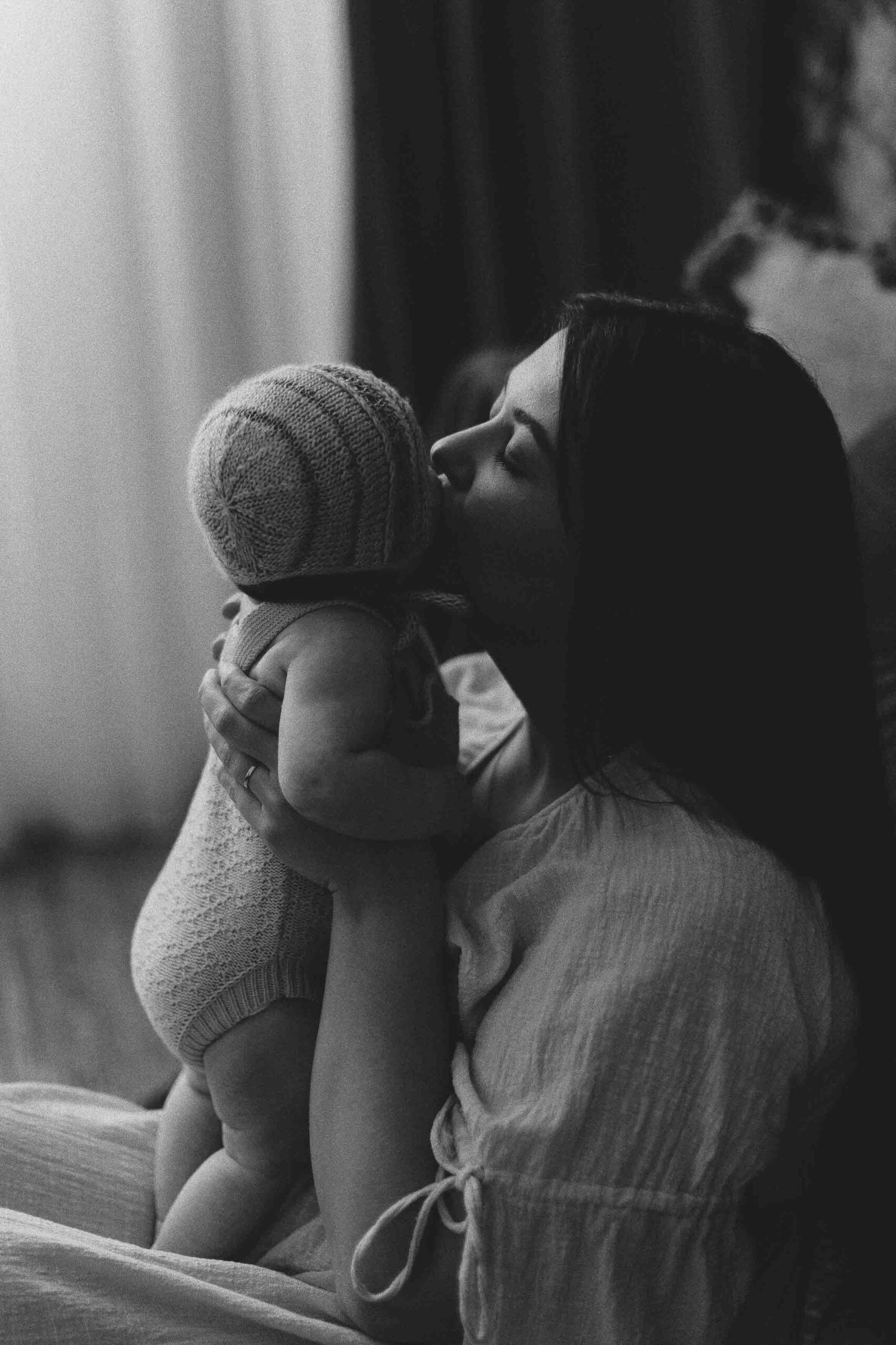 An Adeliade mum holding up her 12 week old baby and giving her a kiss.