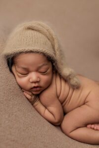 A baby from the Adelaide hills asleep on a blanket wearing a sleepy cap.