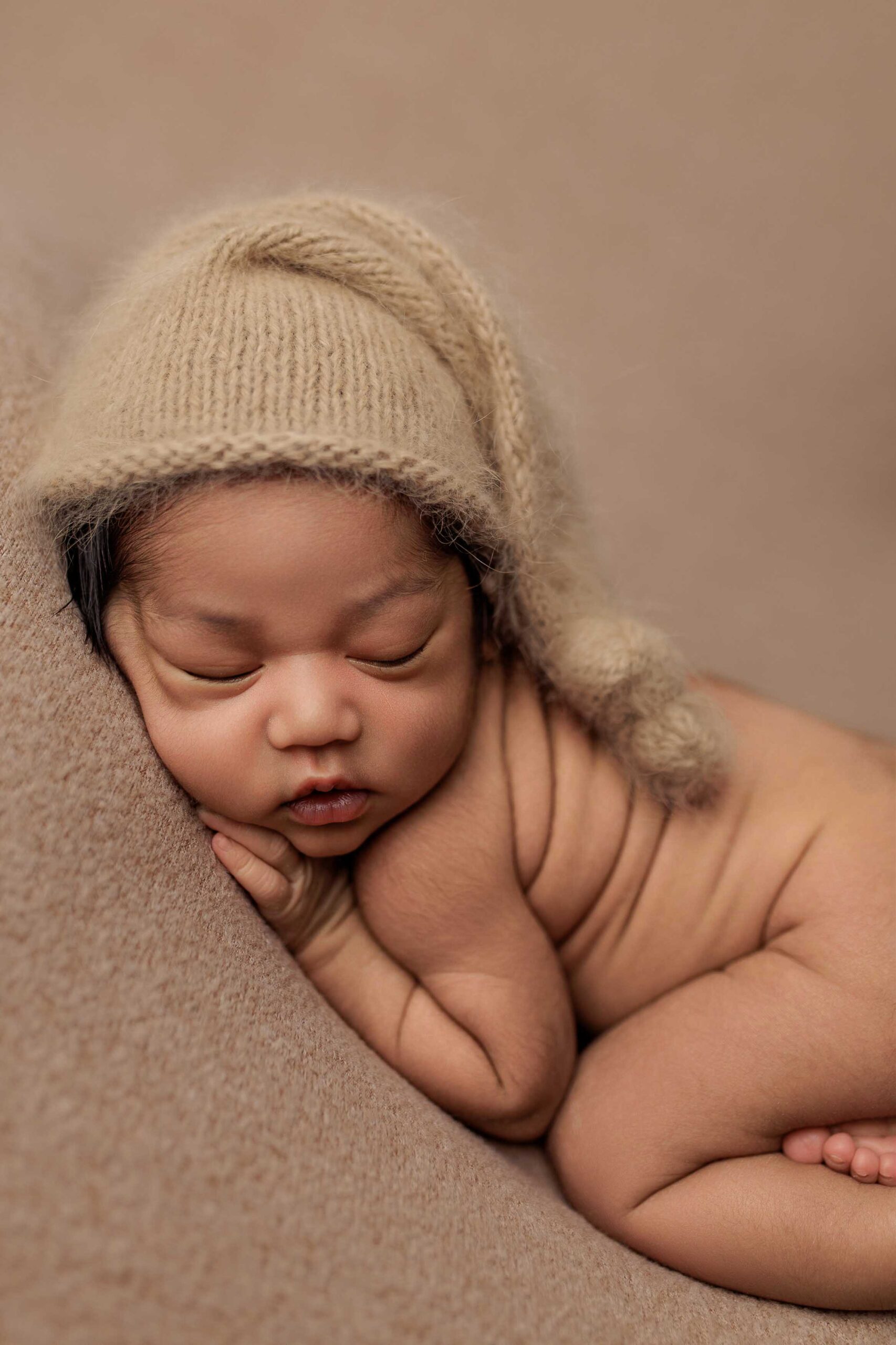 A baby from the Adelaide hills asleep on a blanket wearing a sleepy cap.