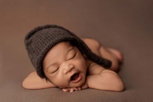 A baby from the Adelaide hills asleep on a blanket wearing a sleepy cap.