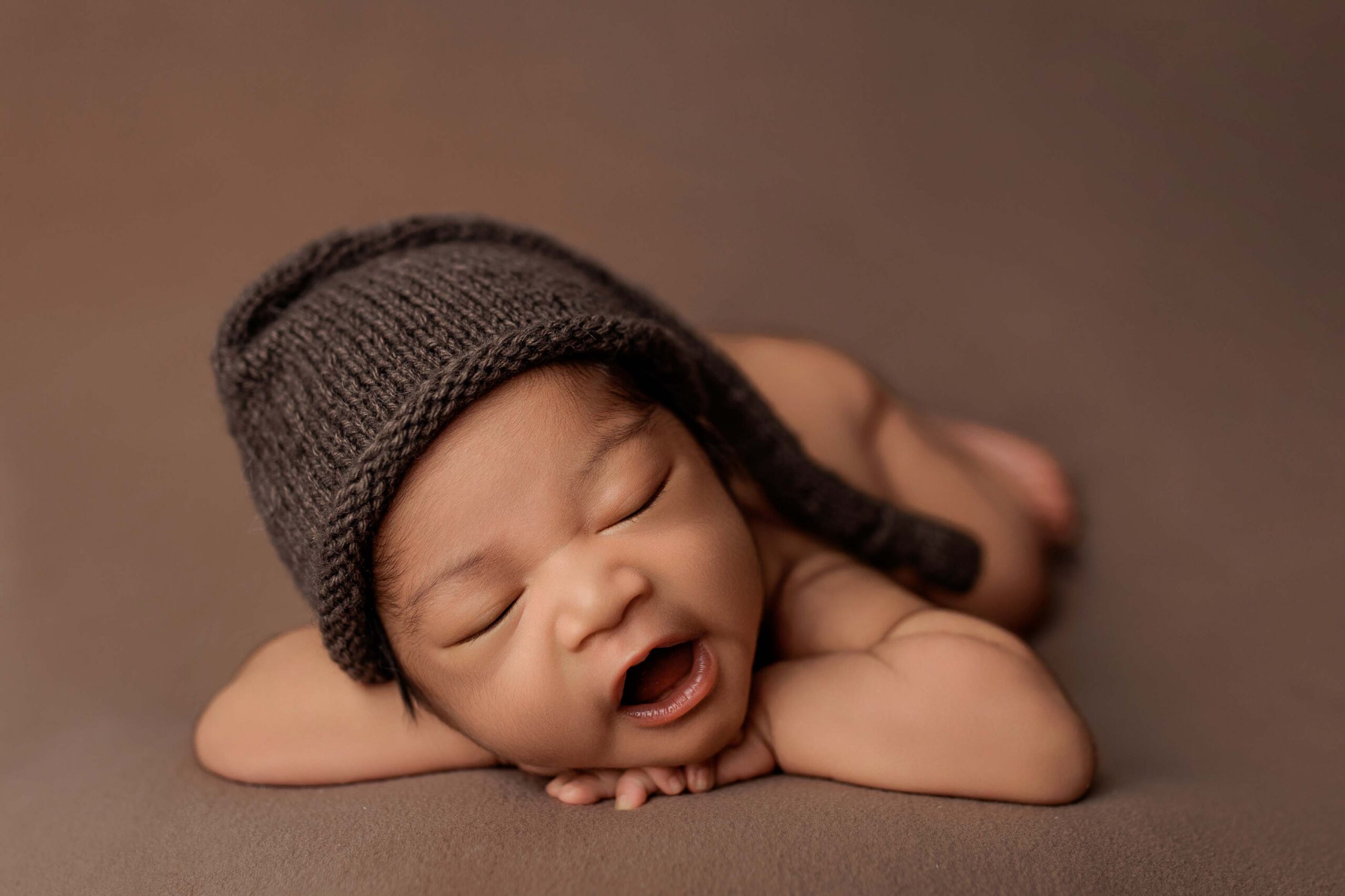 A baby from the Adelaide hills asleep on a blanket wearing a sleepy cap.