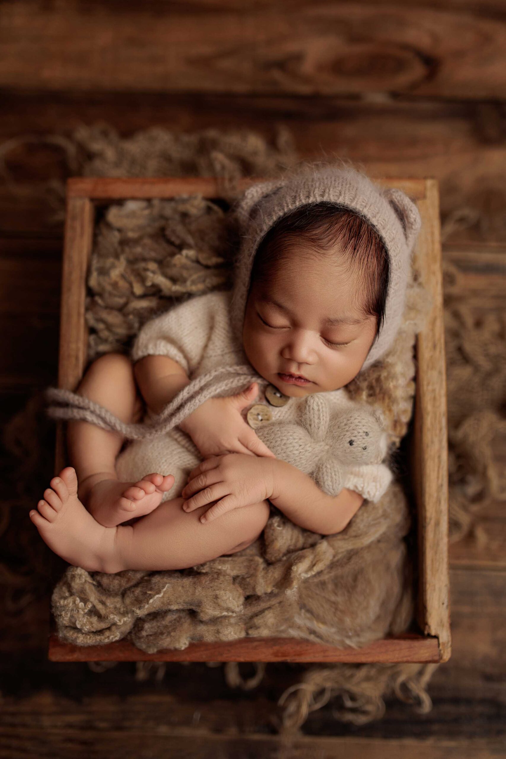 An Adelaide baby in a bear suit asleep in a crate.