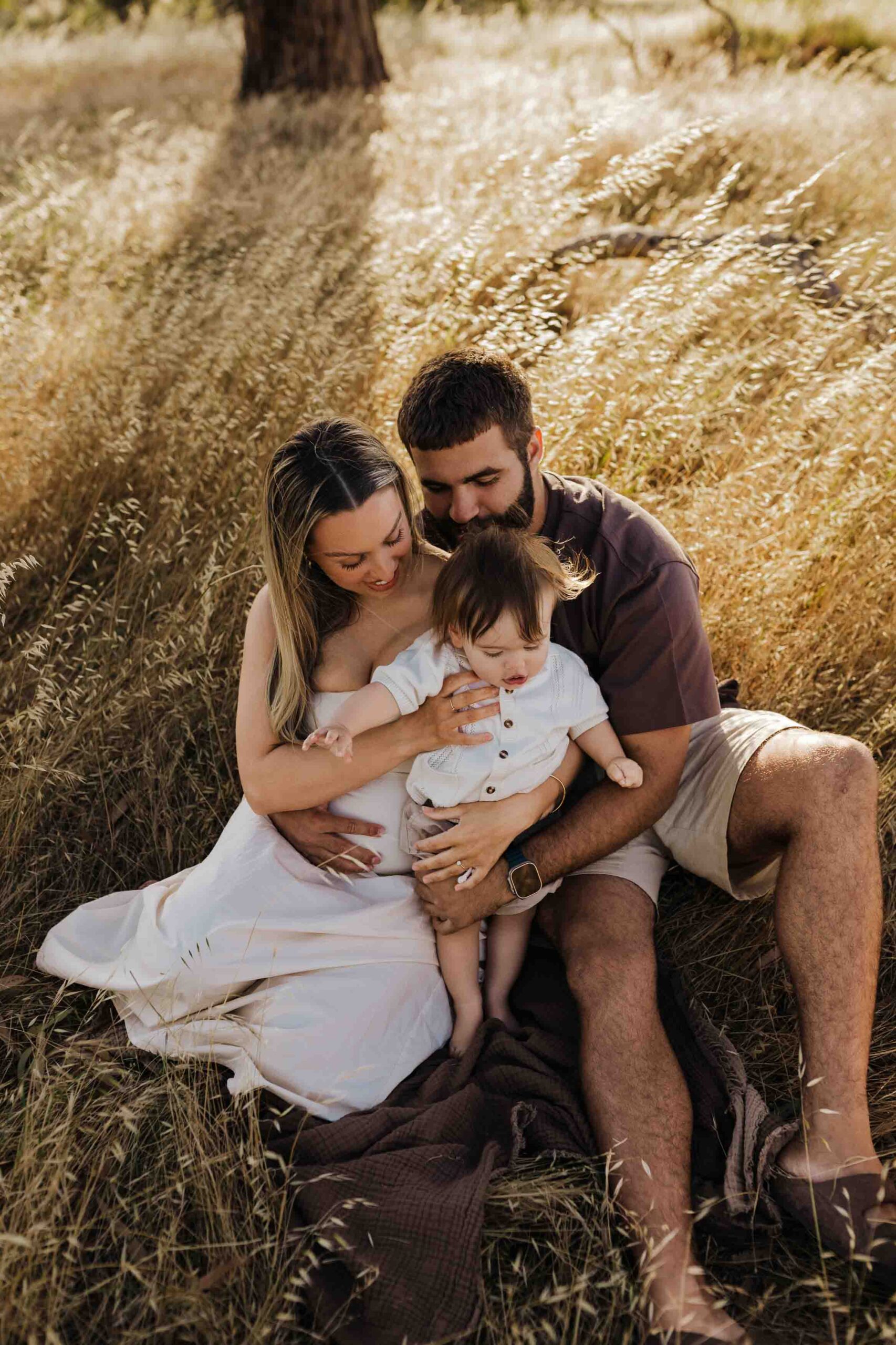 An Adelaide mother and father playing with their 8 month old son outside in a field.