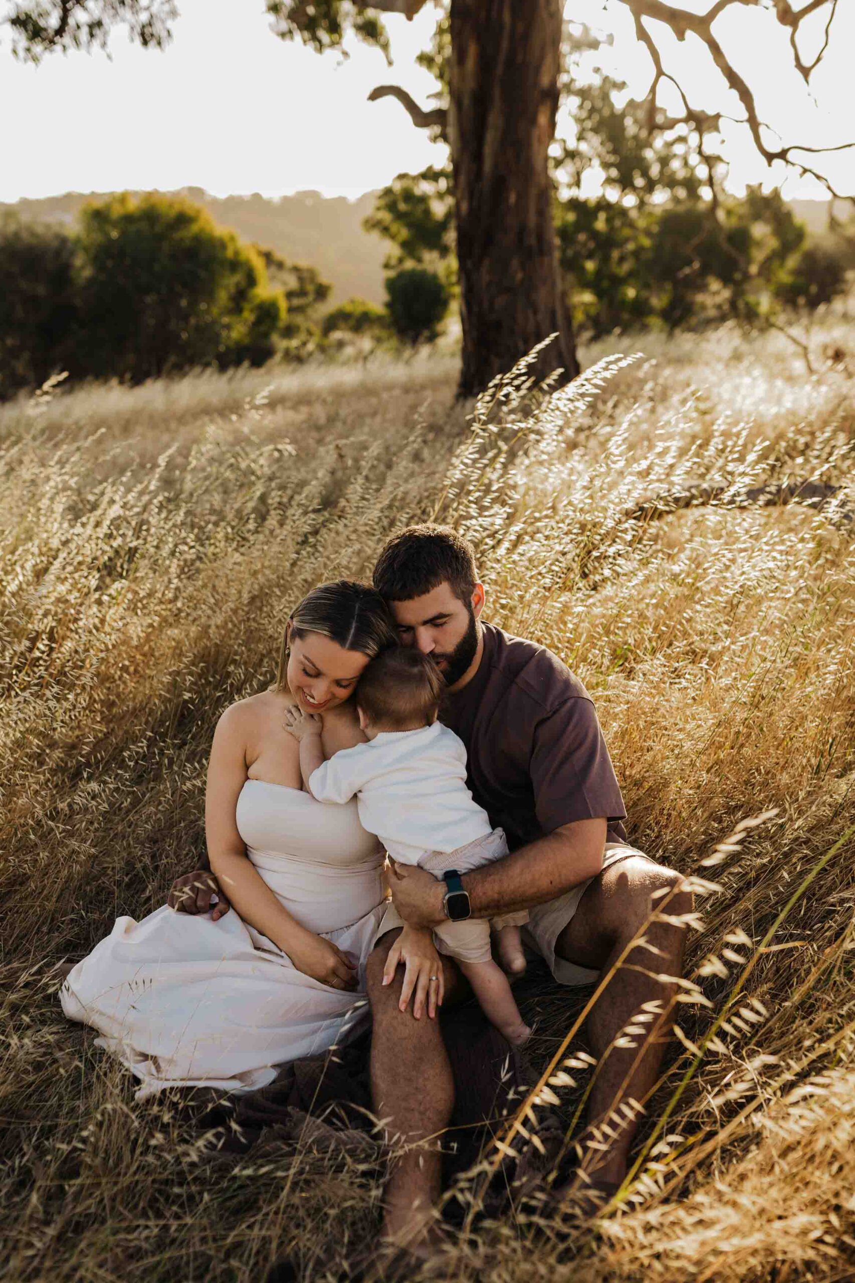 An Adelaide mother and father playing with their 8 month old son outside in a field.