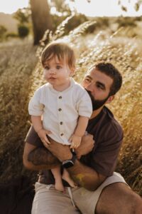 A dad from Adelaide playing in a field with his 8 month old baby son.