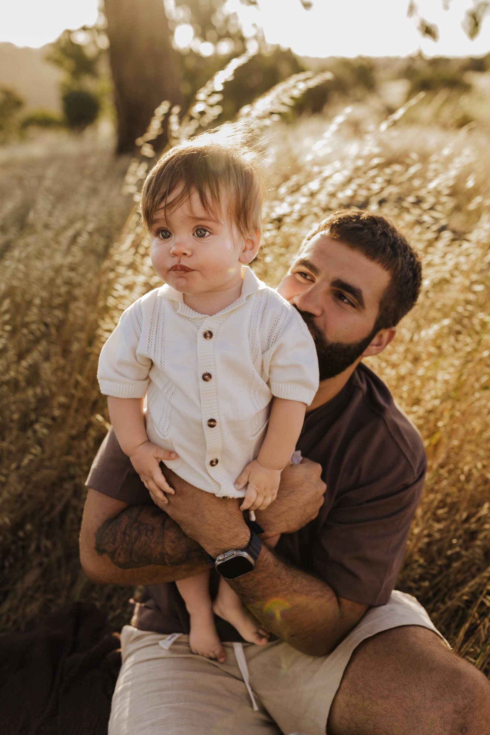 A dad from Adelaide playing in a field with his 8 month old baby son.