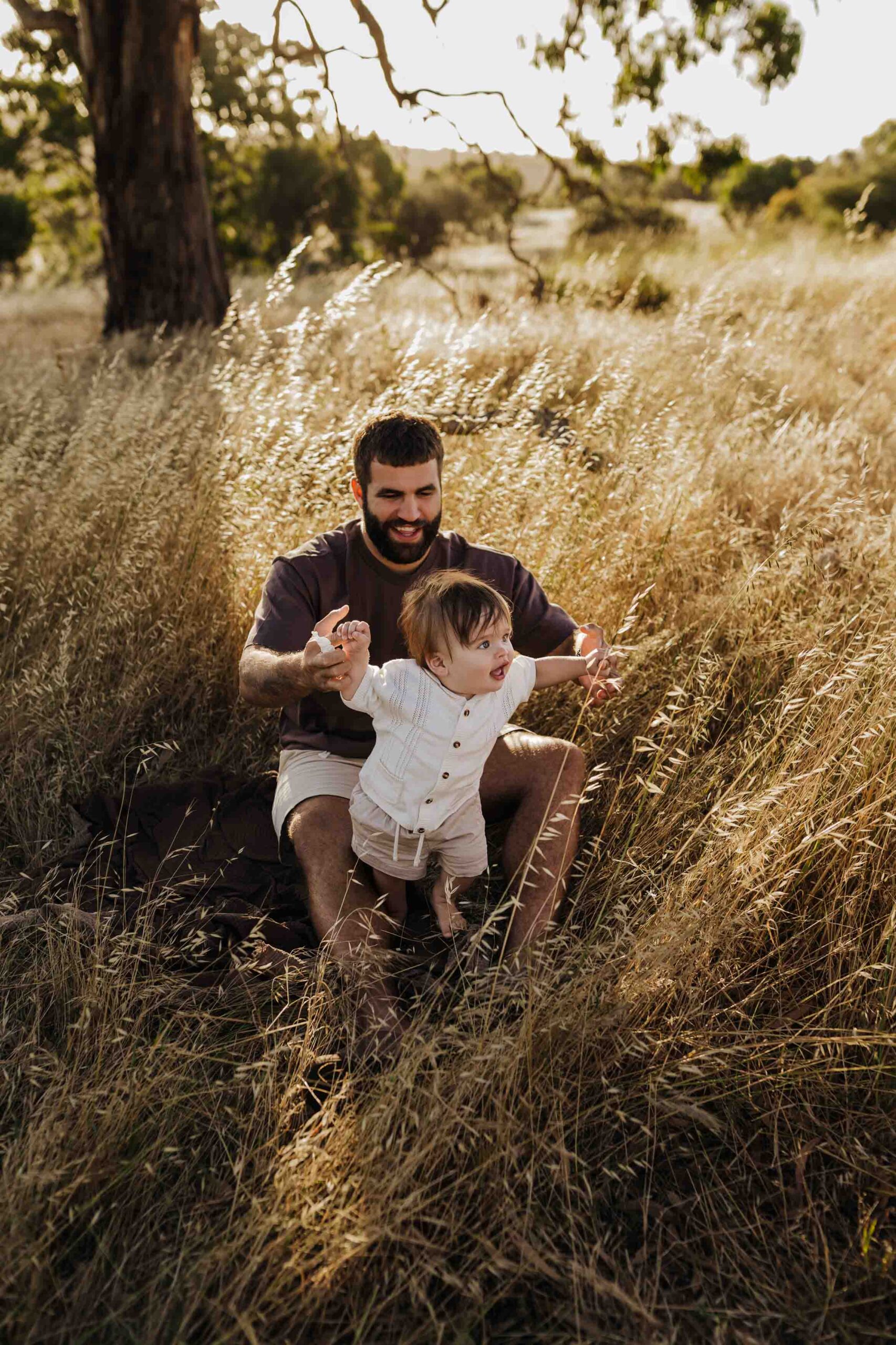 A dad from Adelaide playing in a field with his 8 month old baby son.