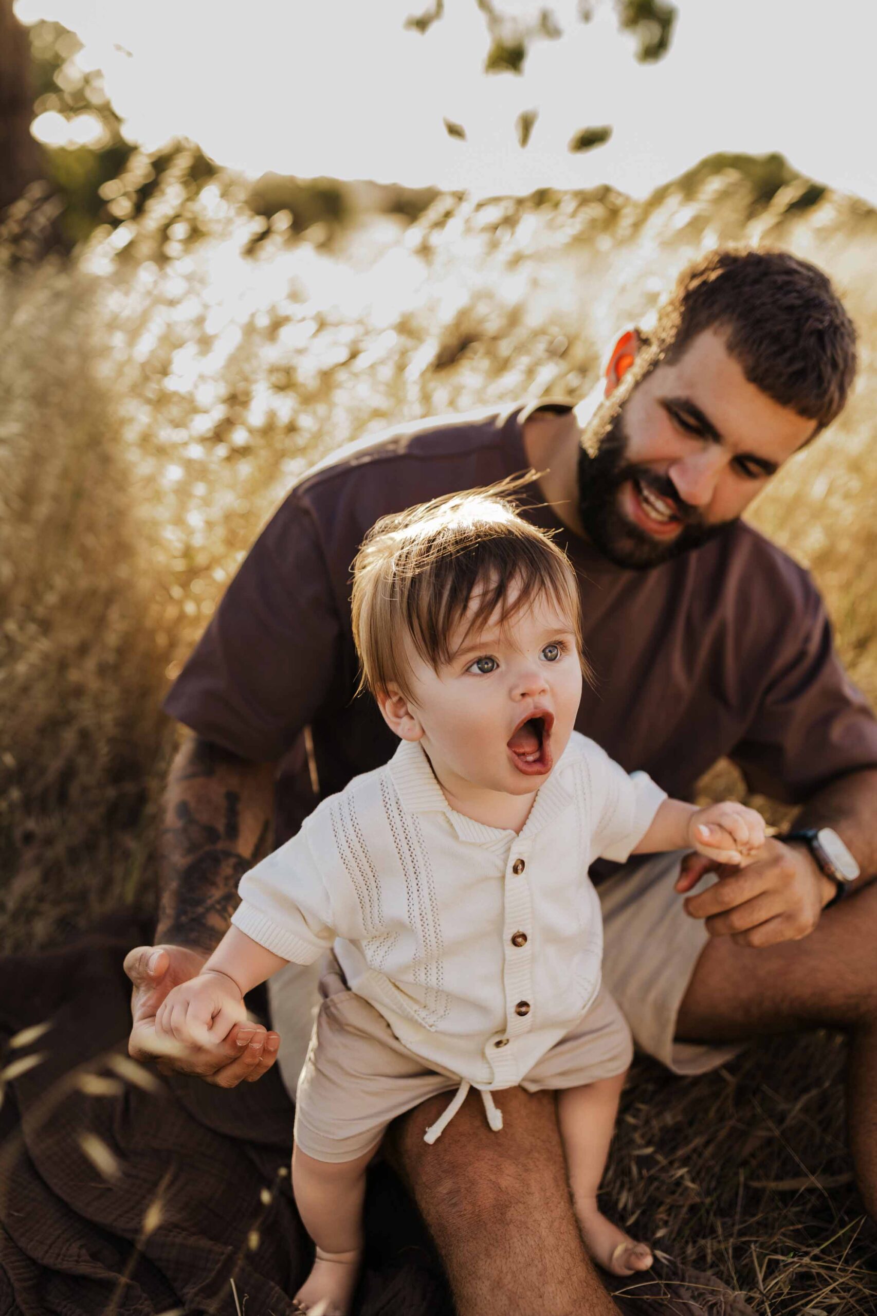 A dad from Adelaide playing in a field with his 8 month old baby son.