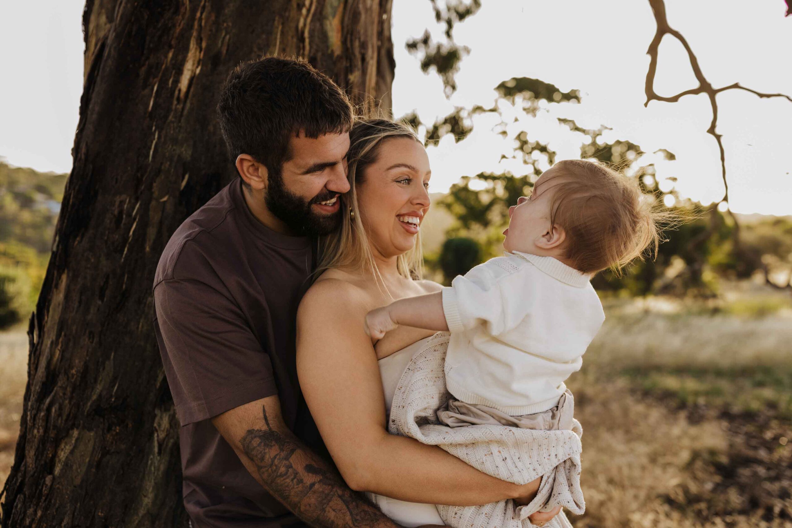 An Adelaide mother and father playing with their 8 month old son outside in a field.