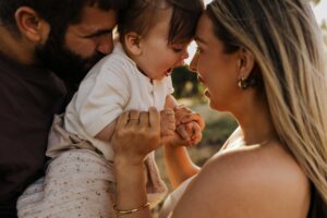 An Adelaide mother and father playing with their 8 month old son outside in a field.