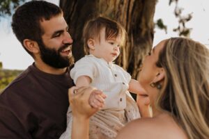 An Adelaide mother and father playing with their 8 month old son outside in a field.