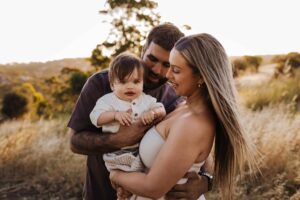 An Adelaide family standing and hugging each other in a field.