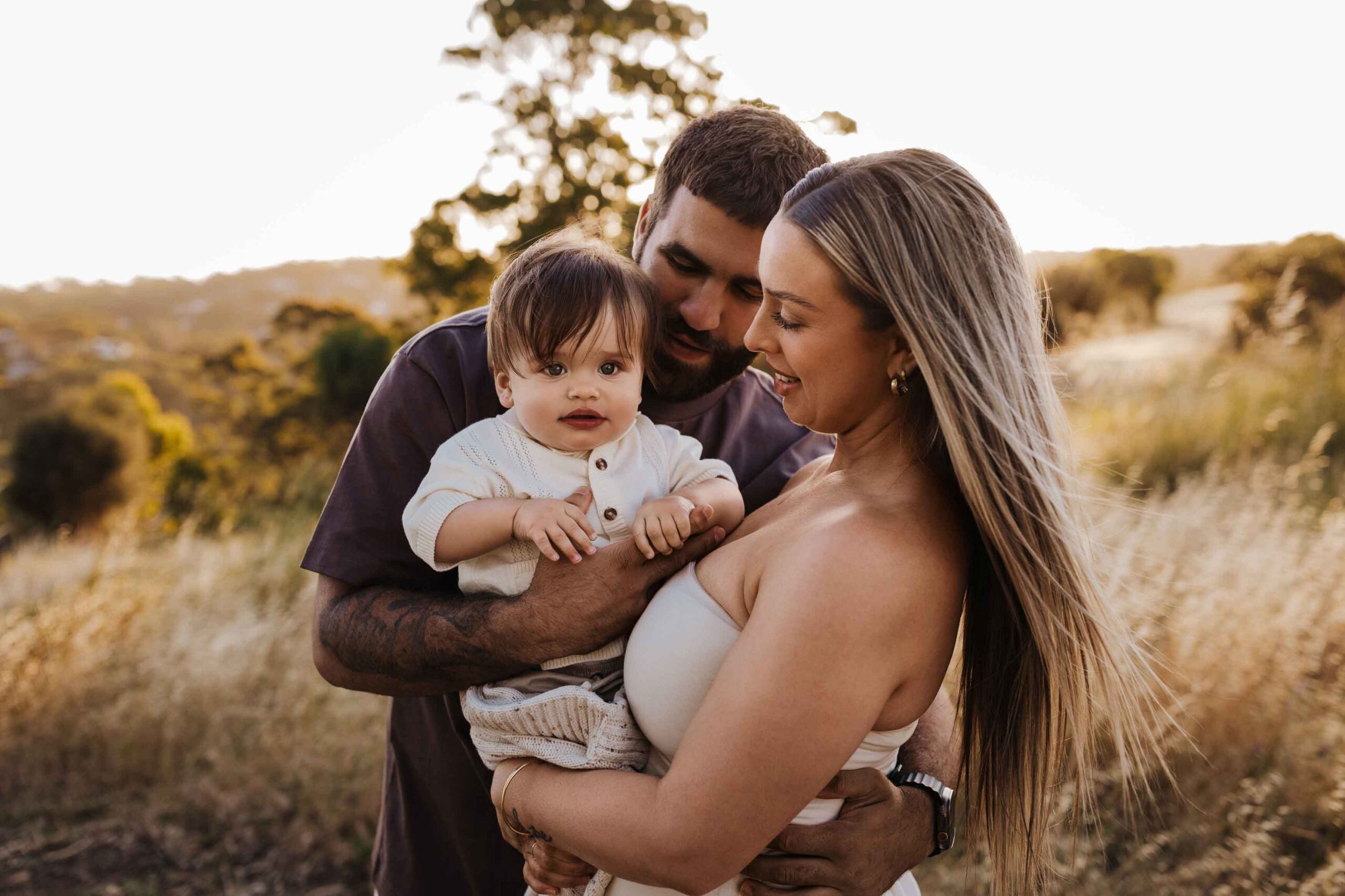 An Adelaide family standing and hugging each other in a field.