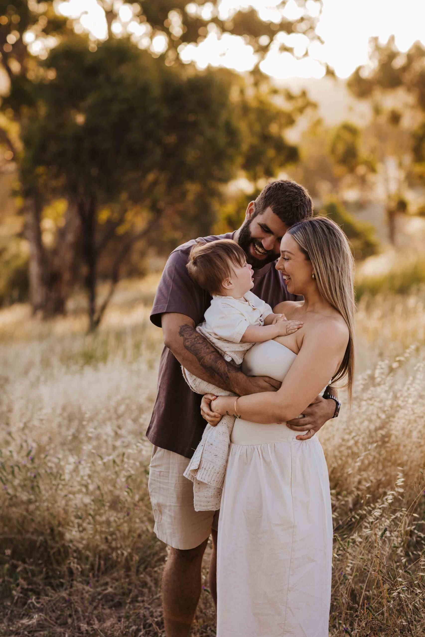 An Adelaide family standing and hugging each other in a field.