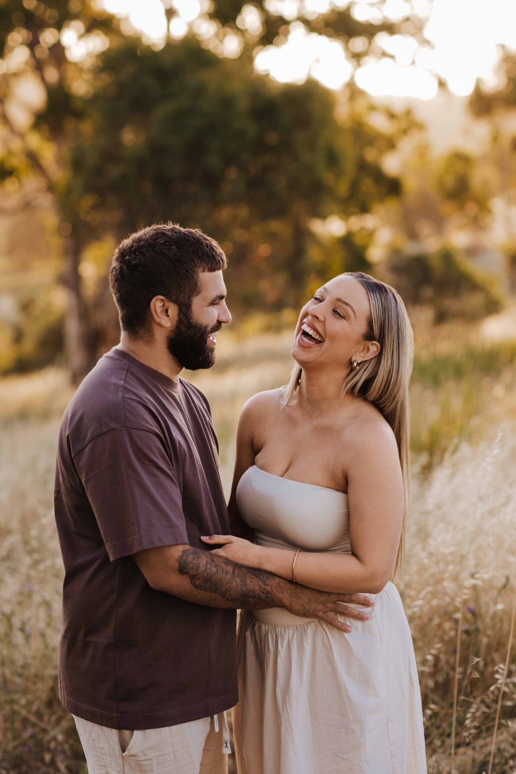 An Adelaide mother anf father laughing together in a field.