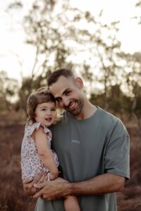 Natural outdoor family photography in Adelaide with parents and young child hugging.