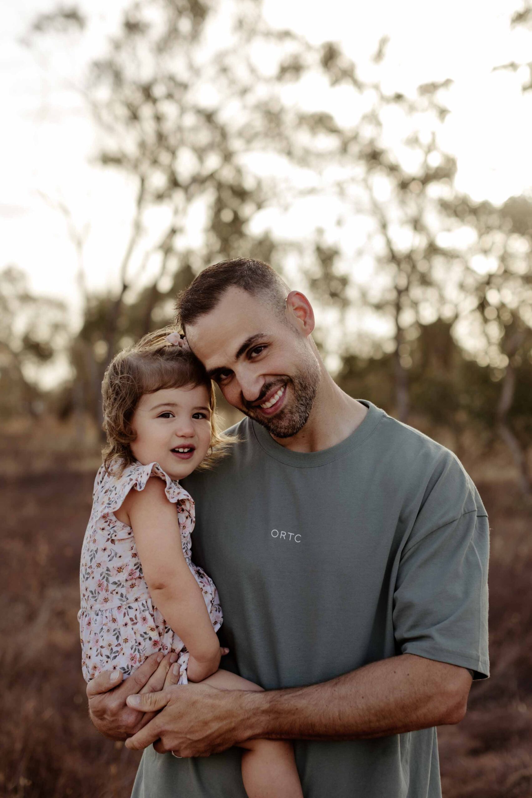 Natural outdoor family photography in Adelaide with parents and young child hugging.