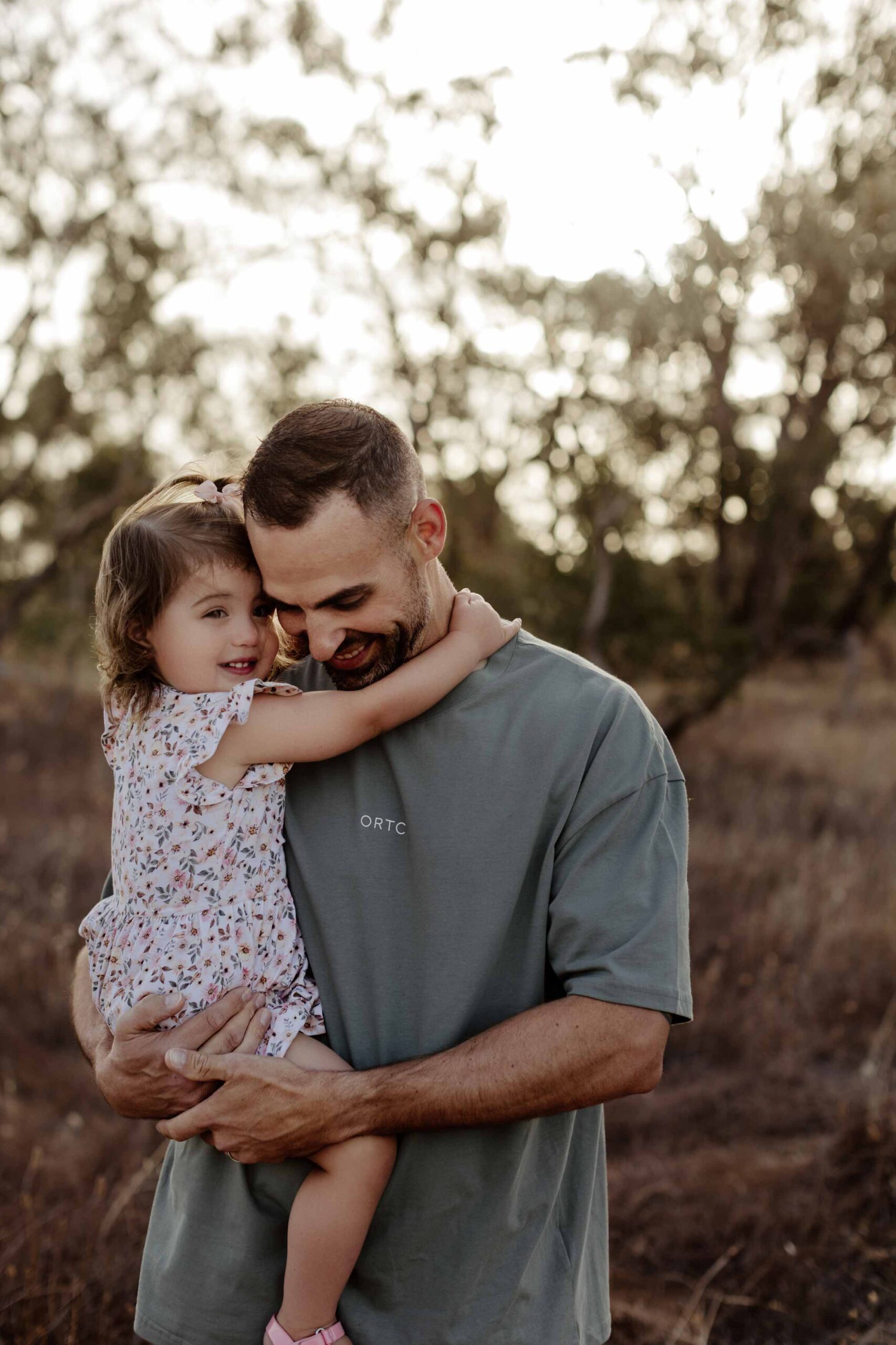 Natural outdoor family photography in Adelaide with parents and young child hugging.
