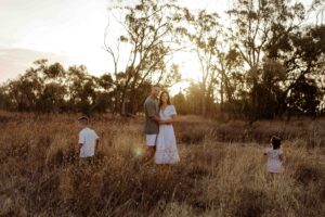 Natural outdoor family photography in Adelaide with parents and young children playing in long grass.