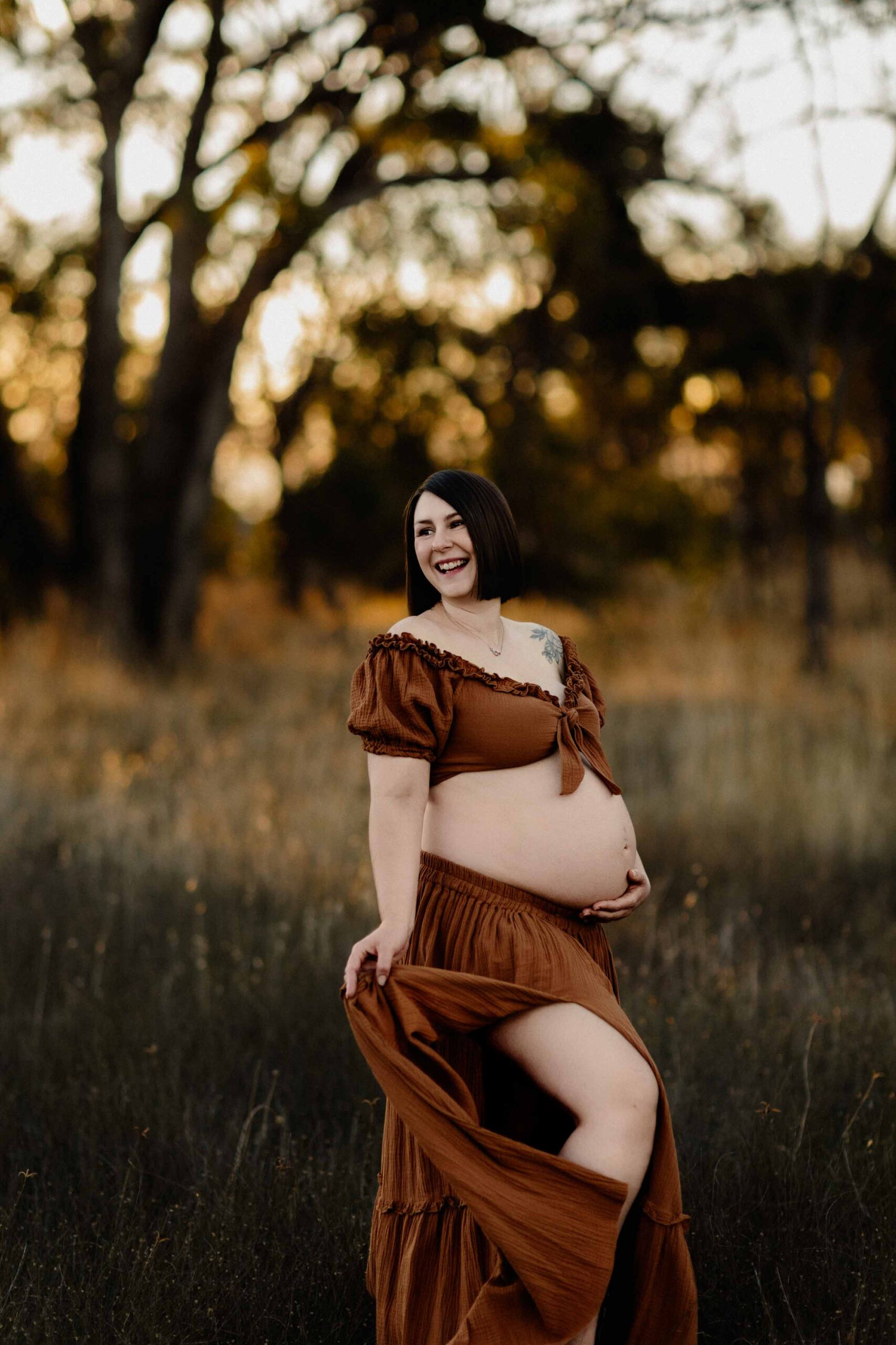 A pregnant mum from Adelaide looking to the side wearing a rust dress at sunset.