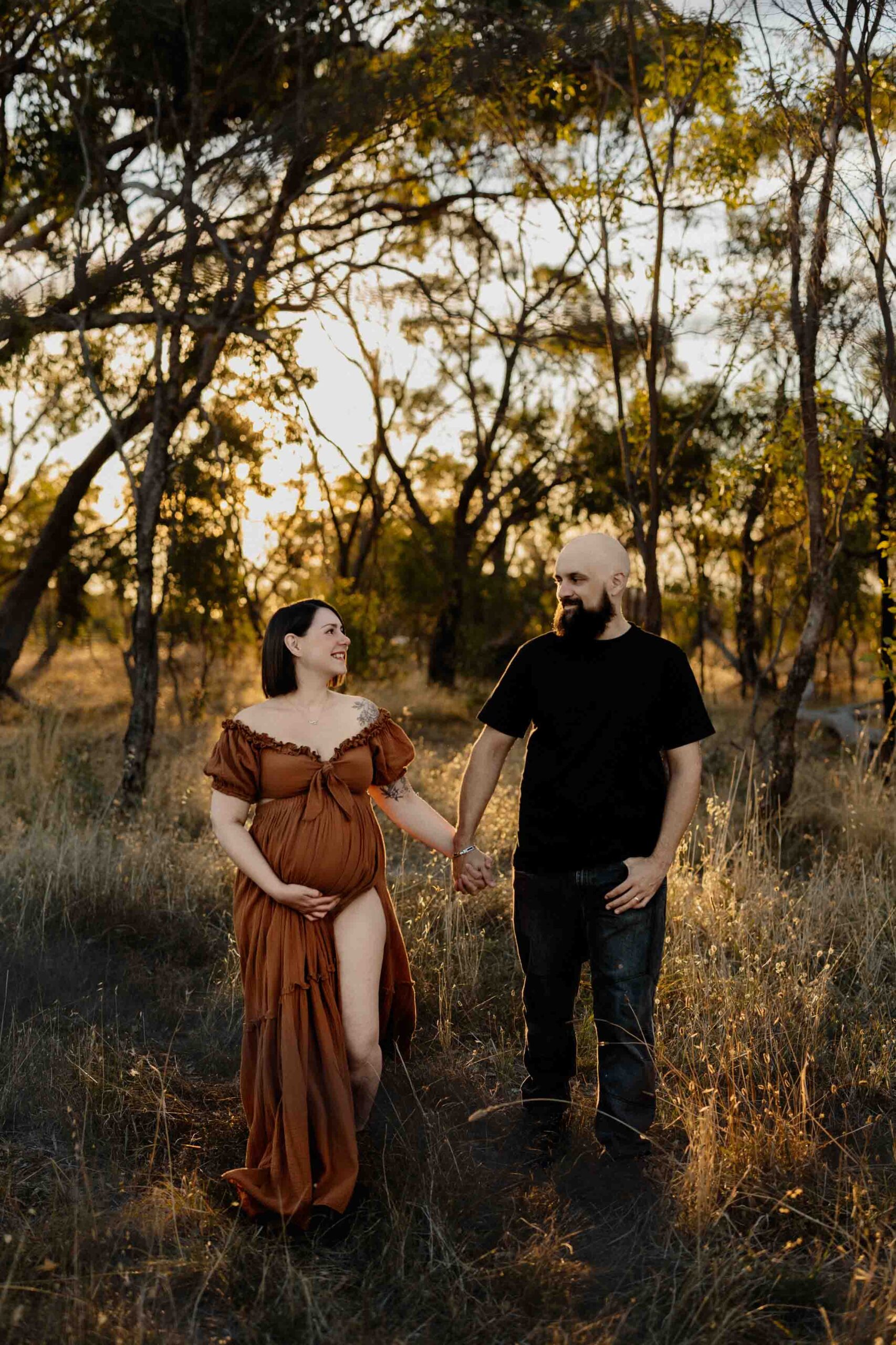 A couple fom Adelaide walking in a field at a maternity session.