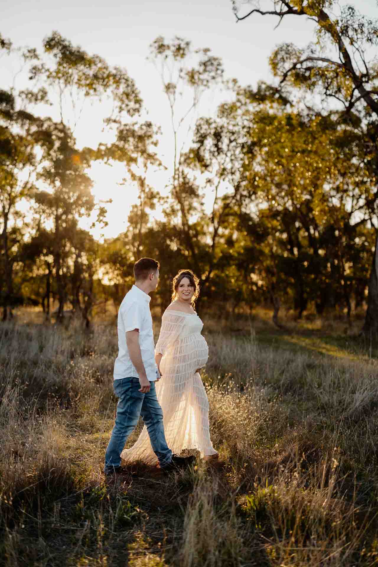 A pregnant mother and her partner walking in sunlight at a maternity session in Adelaide.