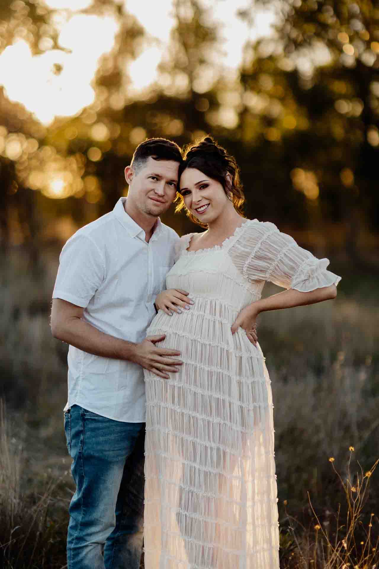 A pregnant mother and her partner cuddling and smiling at a maternity session in Adelaide.
