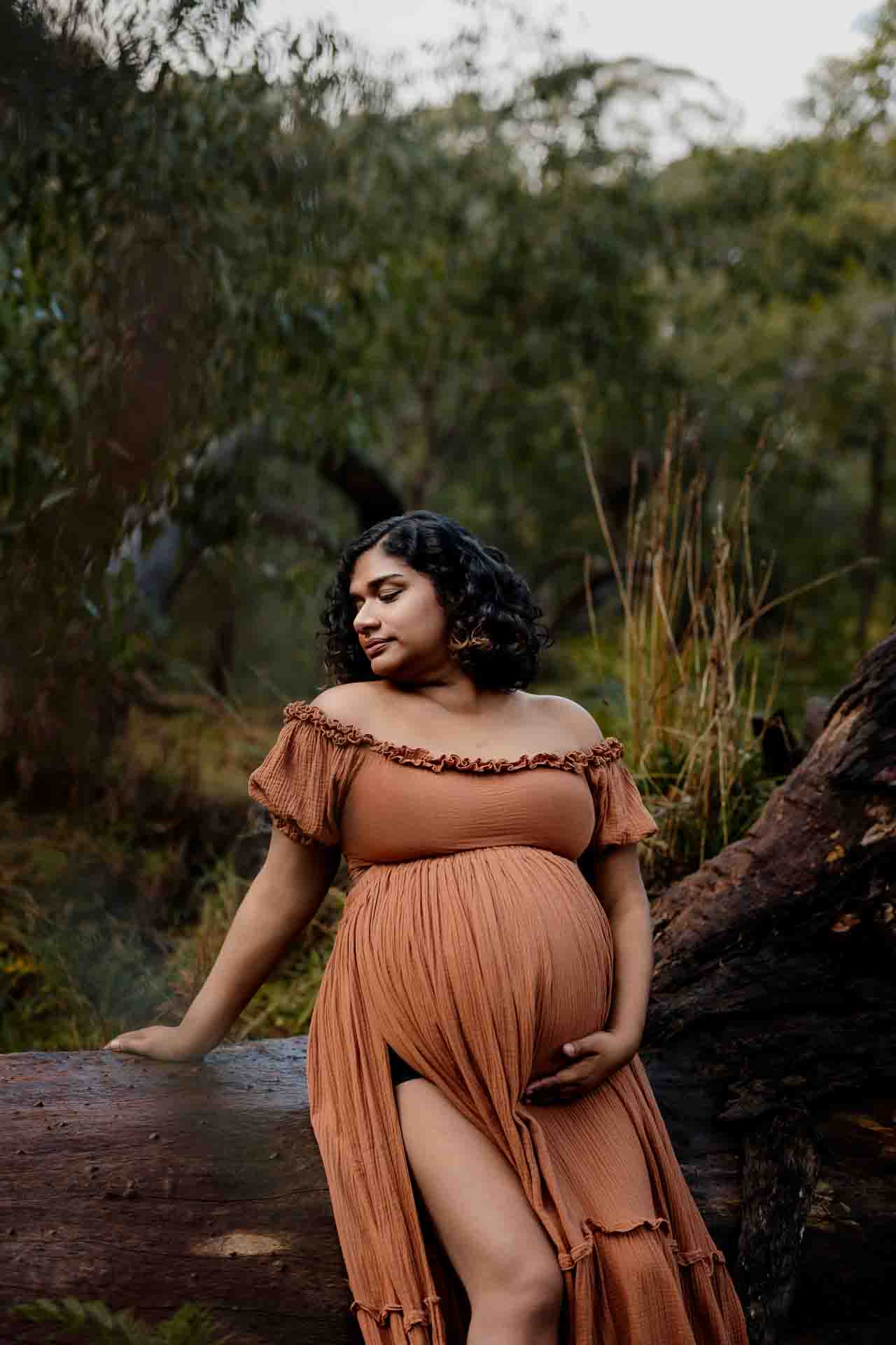 A pregnant mother wearing a rust dress at a maternity session in the Adelaide Hills.