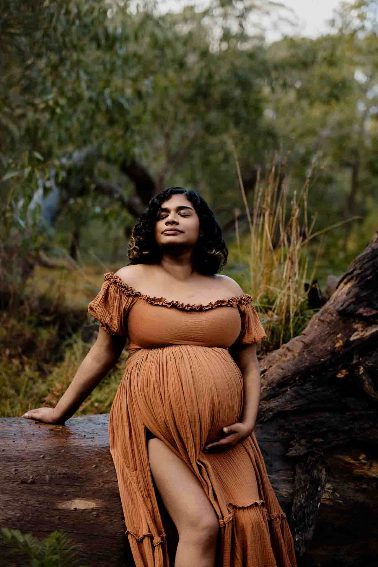 A pregnant mother wearing a rust dress at a maternity session in the Adelaide Hills.