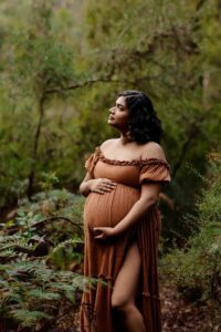 A pregnant mother wearing a rust dress looking up at a maternity session in the Adelaide Hills.