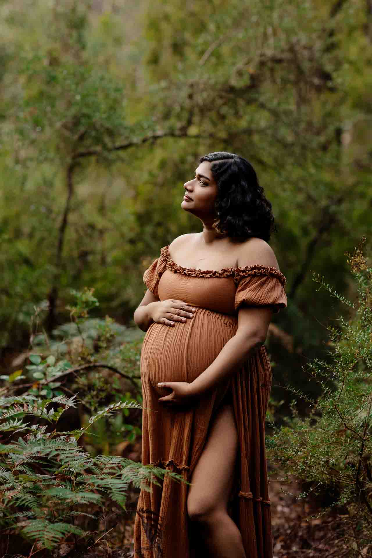 A pregnant mother wearing a rust dress looking up at a maternity session in the Adelaide Hills.