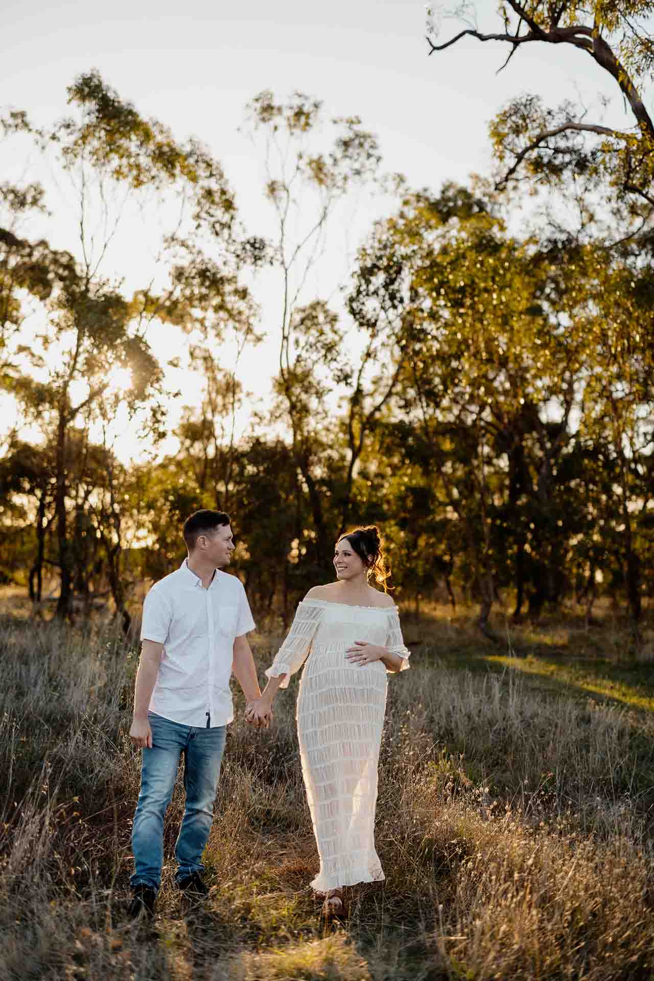 A pregnant mother and her partner strolling in. afield at a maternity session in Adelaide.