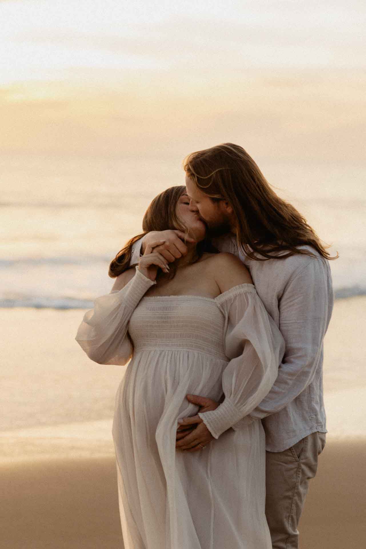 maternity-couple.jpg Couple embracing beside the ocean during a coastal maternity session