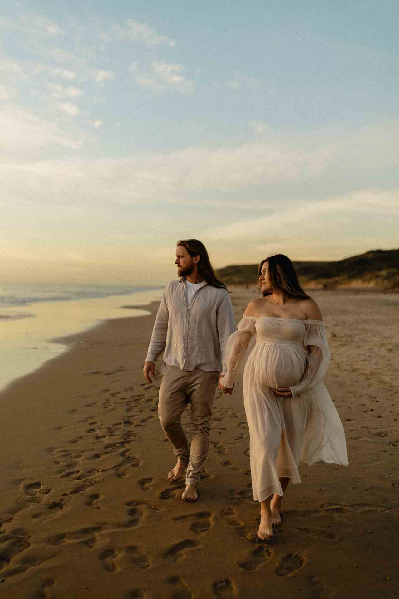 Couple walking together along the beach during a maternity photography session
